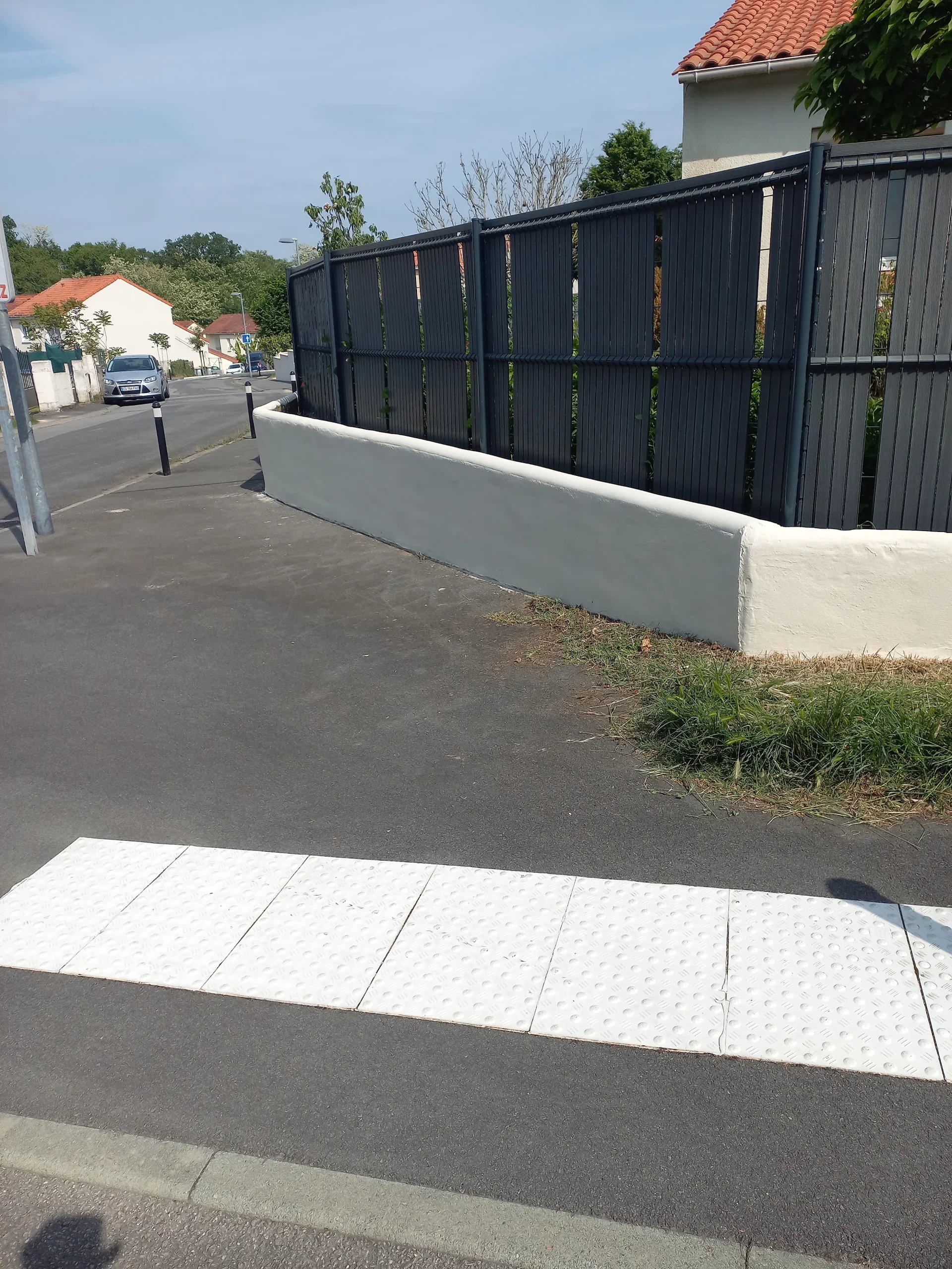 Mur clair et clôture sombre au bord de la rue