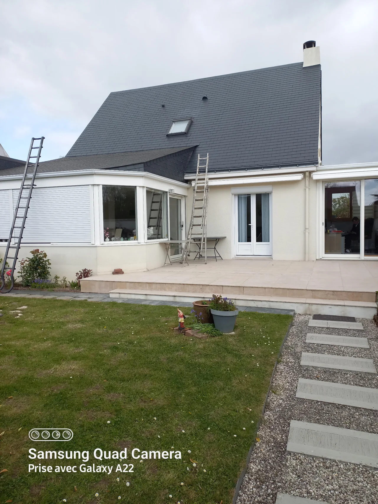 Toiture à la teinte homogène après intervention, au-dessus d’une véranda blanche